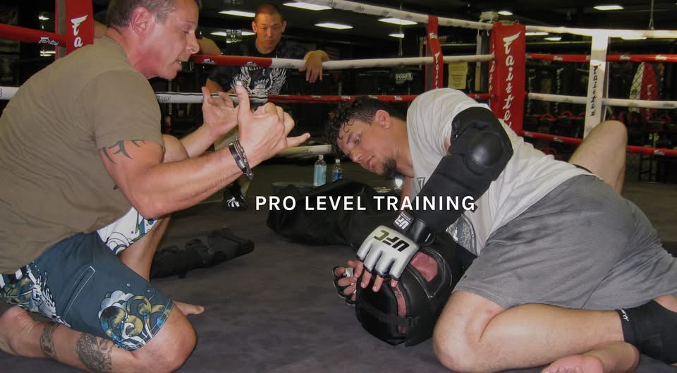 Tony Blauer coaching a fighter on the mat inside a boxing ring