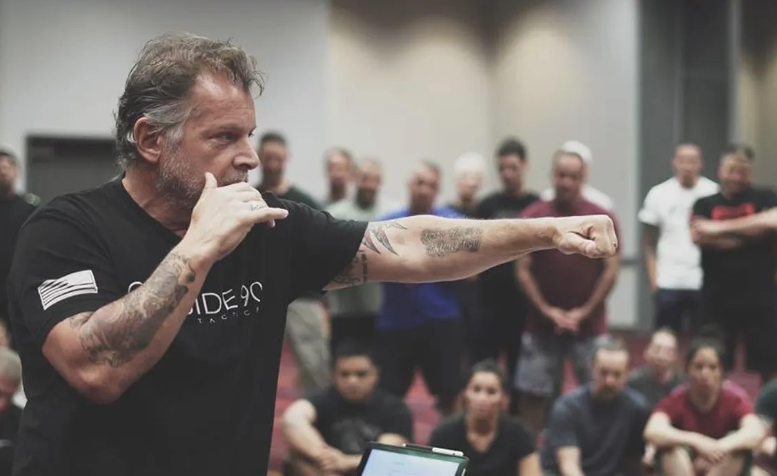 Coach Tony Blauer teaching in front of a room of students